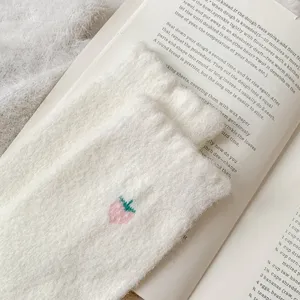 Détail de chaussettes d'hiver duveteuses blanches douillettes avec broderie de fraise.