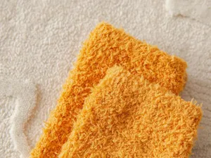Close-up detail of soft coral fleece socks in vibrant orange, ultra-plush winter home sleep wear.