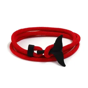 Close-up detail of the red braided rope bracelet with a stylish black whale tail clasp.
