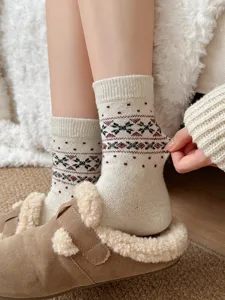 Nahaufnahme kuscheliger dicker Wollmisch-Wintersocken mit traditionellem Schneeflockenmuster.
