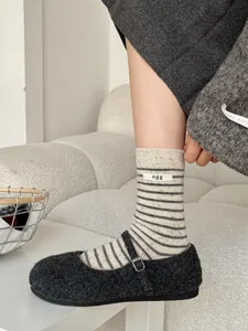 Close-up of women's striped mid-calf wool socks featuring a minimalist egg label design.
