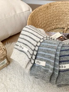 Detail shot of cozy wool striped slouch socks with cute letter label for women autumn winter.