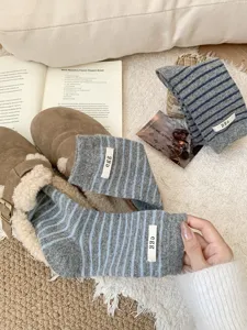 Close-up detail of cozy women wool striped slouch socks featuring cute letter fabric label.