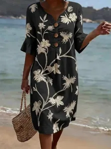 Black V-neck floral embroidered linen dress detail showcasing buttons and beach scene.