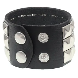Detalle de pulsera punk de cuero negro con tachuelas piramidales metálicas y botones de presión.