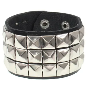 Detalle de pulsera de cuero negro estilo punk con tres filas de tachuelas cuadradas metalicas.