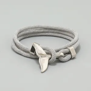 Nahaufnahme des silbernen Walfischschwanz-Anhängers und des geflochtenen Armbands.