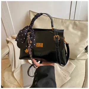 Chic black mini square bag with twist lock and polka dot scarf handle, stylish crossbody.