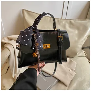 Detailed shot of a chic black fashion handbag featuring a polka dot scarf and gold-tone turn-lock.