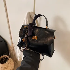Minimalist black handbag for women, stylish small square crossbody bag with chic polka dot scarf.