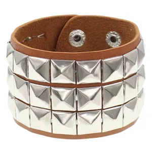 Pulsera brazalete de cuero marron estilo punk con tres filas de tachuelas cuadradas plateadas.