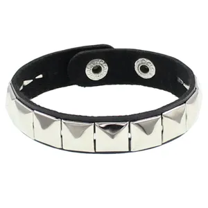 Brazalete de cuero negro con tachuelas piramidales cuadradas metálicas y botón a presión.