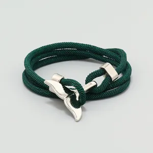 Detailaufnahme des grünen geflochtenen Milan-Seilarmbands mit silbernem Walflossen-Metallverschluss.