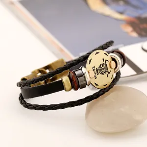 Primer plano detallado de la pulsera de cuero trenzado multicapa vintage con dije del zodiaco.