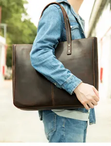 Close-up detail of genuine leather brown tote bag showing contrast stitching and straps.