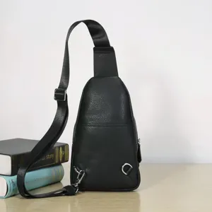 Detailed view of a black genuine leather sling bag featuring durable strap and metal hardware.