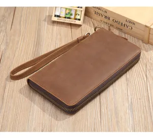 Detailed view of brown leather men clutch bag with wrist strap, business casual style.