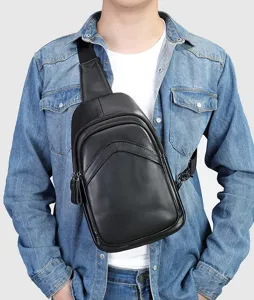 Close-up view of men's black leather sling chest bag worn on model, showing styling and details.