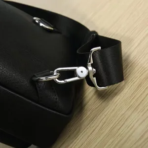 Close-up detail of black leather bag metal buckle strap, high quality hardware accessory view.