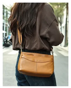Detail shot of brown leather crossbody shoulder bag showcasing texture and front pocket design.
