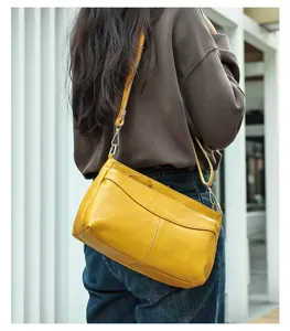 Detailed view of the yellow leather crossbody shoulder bag worn by a model outdoors.