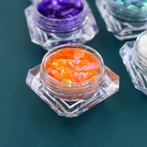 Primo piano di paillettes iridescenti esagonali arancione vibrante in un vasetto trasparente