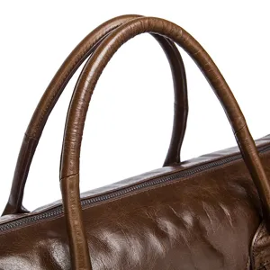 Vue détaillée de la poignée et de la fermeture éclair d'un sac de voyage en cuir.