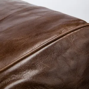 Gros plan sur la texture du sac de voyage en cuir veritable marron et ses details fins.