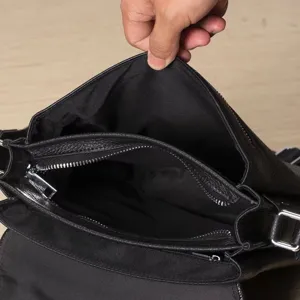 Detailed view of the men's leather messenger bag interior featuring multiple zipper compartments.