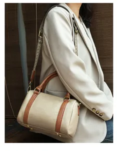 Elegant leather barrel bag for women, featuring stylish brown trim and wide shoulder strap.