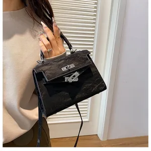 Bolso de mano de moda negro texturizado elegante para mujer, con asa superior y correa de hombro.