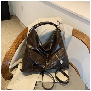 Detailed shot of a vintage dark brown motorcycle style shoulder bag with dual front pockets.