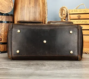 Detailed bottom view of men's genuine leather travel duffel bag with protective metal feet.