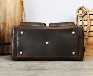 Bottom detail view of men's genuine crazy horse leather travel duffel bag with metal feet.
