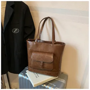 Primo piano della borsa shopper in pelle marrone con tasca frontale in un ambiente accogliente.
