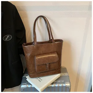 Dettaglio borsa shopper in pelle PU marrone con tasca frontale con patta e cuciture. Uso quotidiano.