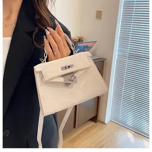 Primer plano detallado del bolso Kelly de cuero blanco crema con cierre giratorio.