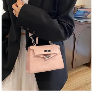 Detalle de bolso de mano de piel rosa con estilo clásico, asa y cierre metálico.