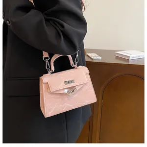 Detalle de bolso de mano Kelly rosa brillante con cierre de giro metálico y correa ajustable.