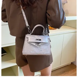 Detalle de bolso de cuero texturizado plateado con cierre de metal y correa elegante.