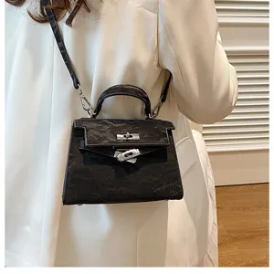 Bolso de hombro negro texturizado con asa superior y cierre metálico para mujer elegante.