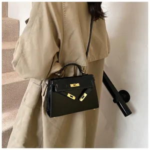 Vue detaillee du sac Kelly en cuir vernis noir, sac a bandouliere tendance mode hiver femme.