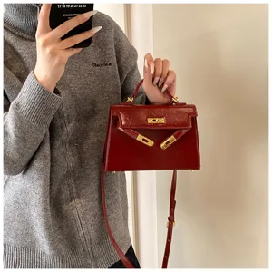 Sac à main vintage pour femme en cuir vernis avec quincaillerie dorée et bandoulière.