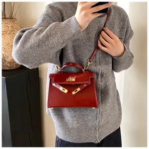 Vue détaillée du sac Kelly en cuir vernis rouge, avec quincaillerie dorée et poignée.