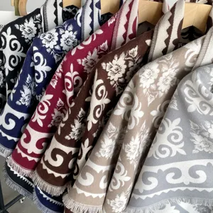 Detailed view of women's jacquard knit imitation cashmere shawls in various colors with fringe.