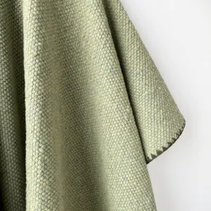 Primer plano de la textura de un chal de punto verde, mostrando tejido y costura.