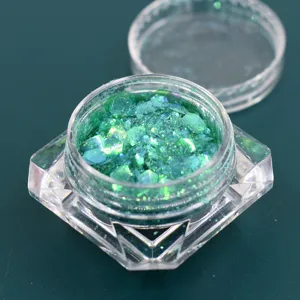 Primo piano di paillettes verdi cangianti in un vasetto trasparente sfaccettato lusso