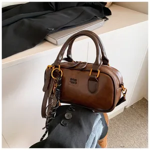 Close-up of retro brown bowling handbag featuring premium leather texture and luxury gold hardware details.