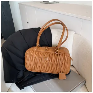 Close-up detail of stylish brown quilted shoulder bag with soft leather and double handles.