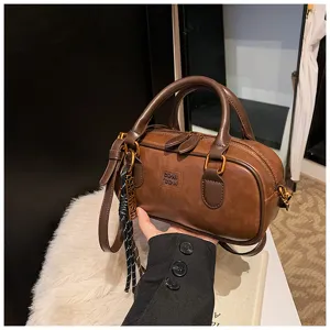 Retro brown bowling shoulder bag with double top handles, zipper closure, and chic metal charm.